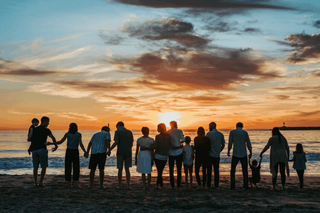 A family embraces one another on the beach in front of a sunset
