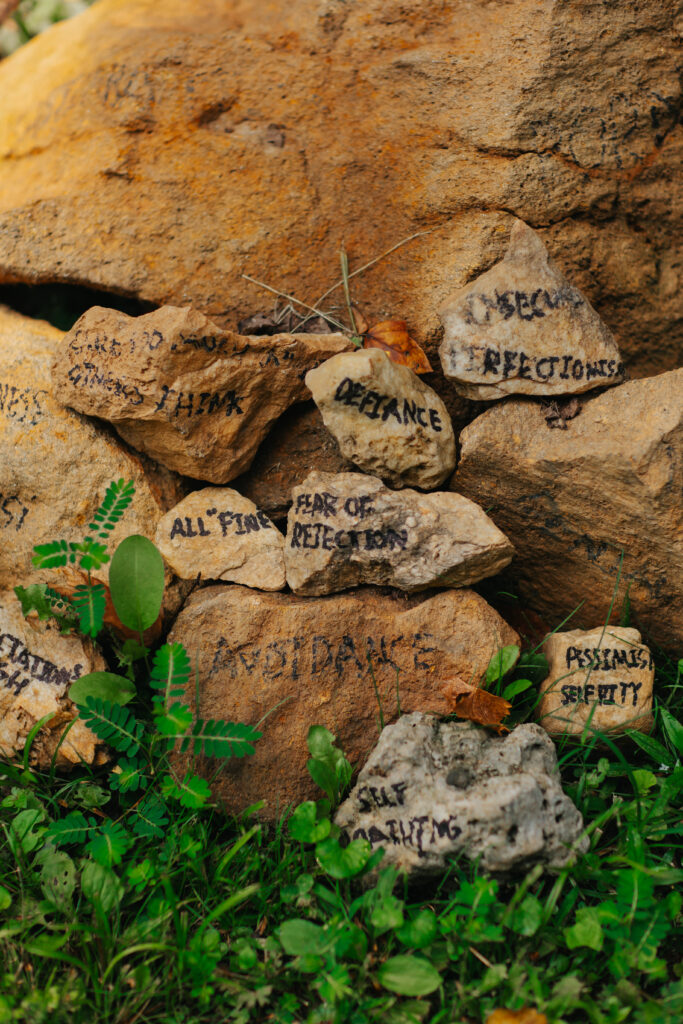 Rocks painted with negative habits that have been released by men overcoming addiction: avoidance, defiance, fear of rejection