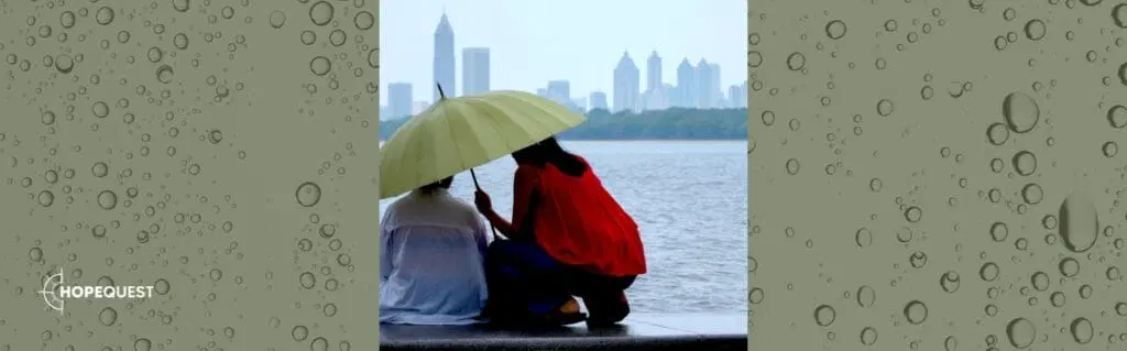 Two adults share an umbrella outdoors